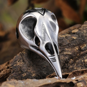 Macro detail of gothic viking crow skull ring on textured wood background showing carving