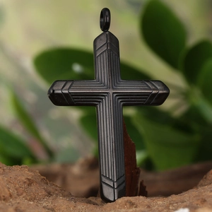 Macro detail of a black cross pendant with geometric linear patterns on a stone base