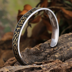 Detailed view of Viking cuff bracelet with Nordic runes and Celtic patterns on old bark