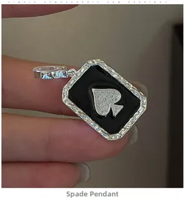 Detail of vintage silver spade pendant with black enamel inlay held by hand