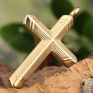 Macro shot of gold cross pendant with 3D stripe textures on natural bark background
