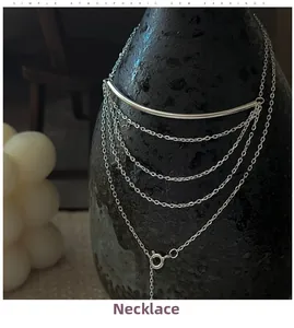 Detail of silver multi-layer fringe necklace with curved bar on textured vase