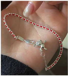 Dettaglio del bracciale rosso intrecciato con ciondolo a maialino in argento S925