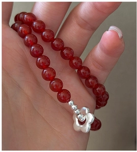 Detail of S925 silver flower charm and vibrant red agate beads on a beaded bracelet
