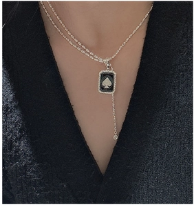 Detailed view of an S925 silver spade pendant necklace with black enamel and tassel