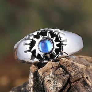 Punk style silver metal ring with blue gemstone center on natural bark background
