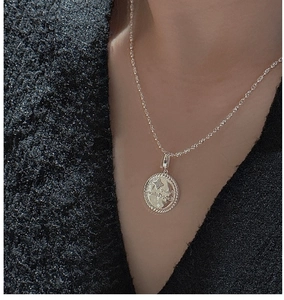 Detail of vintage S925 sterling silver star coin pendant necklace on female model