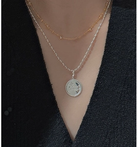 Close-up of S925 silver layered necklace set with a star engraved coin pendant