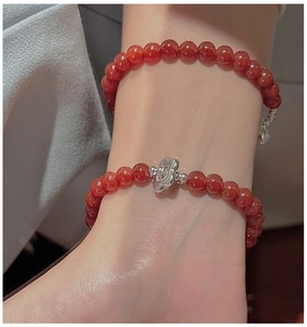 Macro view of double-layered red agate beaded bracelets with a silver flower charm