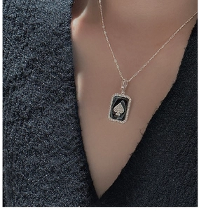 Close-up of S925 silver spade pendant necklace worn on a black textured sweater