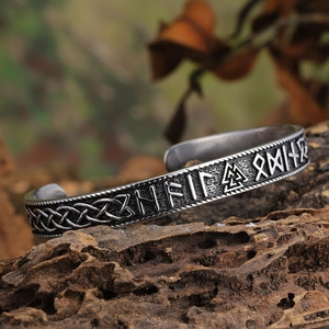Vintage Mjolnir Viking cuff bracelet with Valknut runes on a natural wooden background