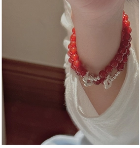 Detail of double-layer bracelet with red agate beads and silver floral charms on wrist