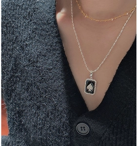 Close-up of vintage S925 silver spade pendant layered with chains on a model sweater