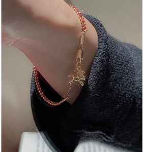 Dettaglio del bracciale con perline rosse e oro, ciondolo a cavallo e chiusura a moschettone