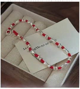Macro shot of S925 sterling silver fish charms and braided red cord bracelet detail