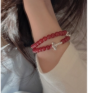Detail of S925 silver double-strand beaded bracelet with red agate flower charm on wrist