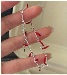 Detail of S925 silver chain bracelet featuring red woven knots and a small heart charm