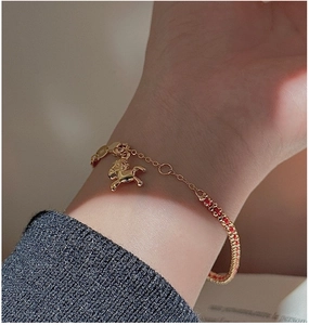 Dettaglio del ciondolo a cavallo dorato in argento S925 su bracciale di perline rosse