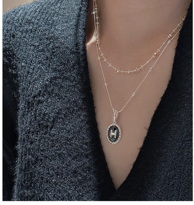 Dettaglio di collana a strati in argento con ciondolo rotondo in smalto nero H