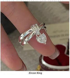 Macro view of layered S925 silver ring featuring a dangling heart-shaped zircon charm