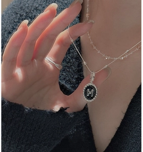 Dettaglio del ciondolo in argento S925 con lettera H in smalto nero e bordo a corda