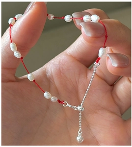 Détail du bracelet en corde rouge avec perles d'eau douce et petit pendentif cœur argenté