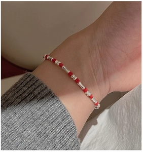 Detaillierte Nahaufnahme eines roten Armbands mit silbernen Bambus-Elementen am Handgelenk