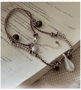 Macro view of S925 silver waterdrop pendant with brushed texture and tiger eye beads