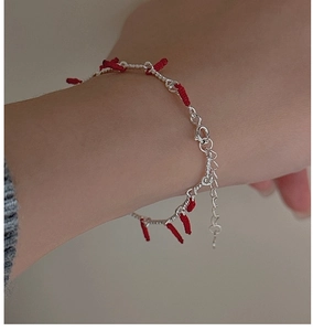 Close-up of S925 sterling silver bracelet with red knot accents on a female wrist