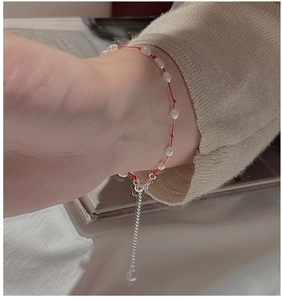 Gros plan d'un bracelet en fil rouge avec petites perles sur le poignet d'une femme