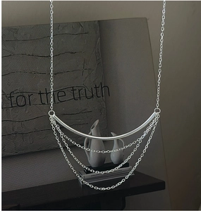 Detail of minimalist S925 sterling silver multilayered tassel necklace on a textured background