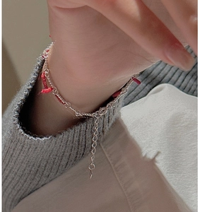 Close-up of S925 sterling silver chain with red braided thread on woman wrist