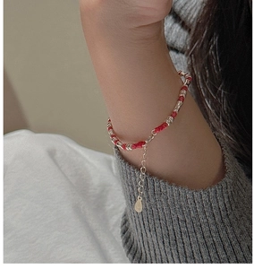 Detail von rotem Textilarmband mit S925 Sterlingsilber Perlen an einem Strickärmel