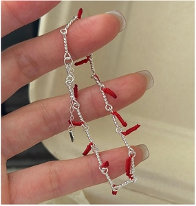 Detailed macro of S925 silver bracelet with red lucky knots and heart pendant