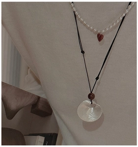 Detail of layered S925 silver necklace with red heart pearl and silver disc pendant