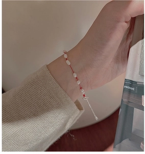 Gros plan d'un bracelet en corde rouge avec perles baroques sur le poignet d'un mannequin