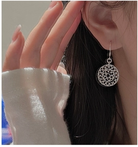 Close-up of S925 sterling silver filigree hollow floral drop earrings on a model