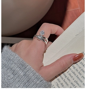 Close-up of S925 sterling silver heart-shaped zircon ring on a hand with book background