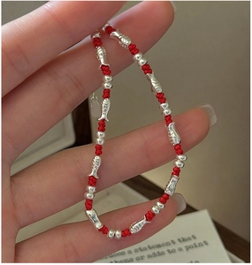 Detailed shot of S925 silver fish charms on a handmade red braided rope bracelet