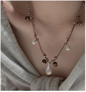 Detail of woven rope necklace featuring tiger eye beads and matte silver waterdrop pendants
