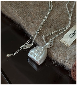 Détail du pendentif sac en argent S925 avec cœurs en relief et chaîne à fermoir mousqueton
