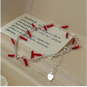 Detail of S925 sterling silver bracelet with red thread accents and silver heart charm