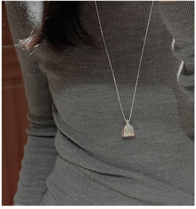 Détail du pendentif sac en argent S925 sur pull en maille grise avec finition mate