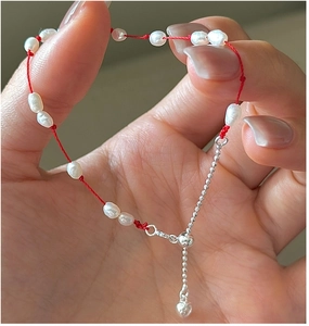 Détail du bracelet en cordon rouge avec perles baroques et pendentif cœur ajustable