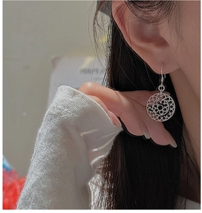 Close-up of S925 sterling silver earrings with intricate bohemian hollow pattern on model