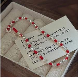 Close-up of S925 sterling silver fish charms on a woven red rope bracelet detail