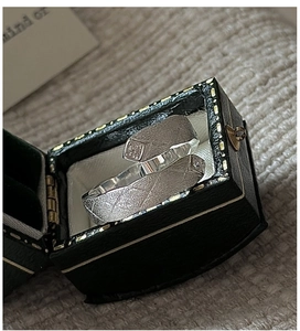 Close-up of S925 sterling silver couple rings with matte cross texture in a gift box
