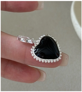 Close-up of S925 sterling silver heart pendant with black enamel and beaded edge detail