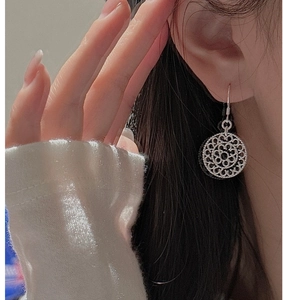 Macro shot of silver hollow geometric floral earrings worn for a vintage elegant look