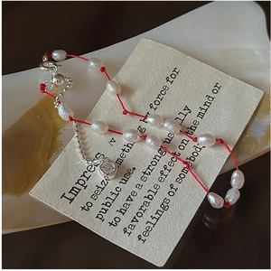 Vue détaillée du bracelet en cordon rouge avec perles d'eau douce et pendentif en cristal